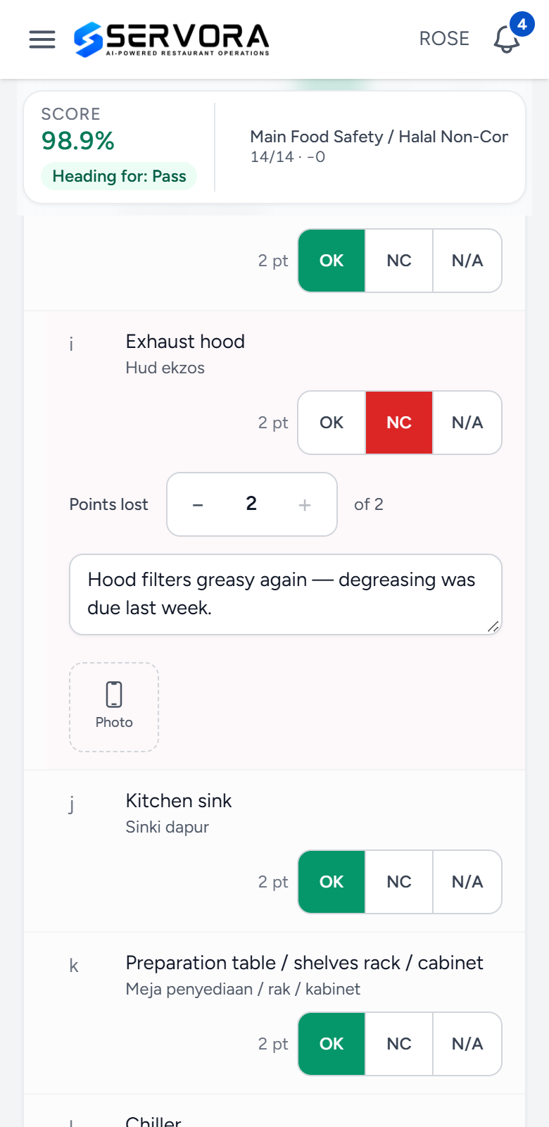 A ROSE audit in progress on a phone at Demo Bistro Bangsar: score 98.9% heading for Pass, and the Exhaust hood marked NC with 2 points lost, the note Hood filters greasy again, degreasing was due last week, and a Photo button