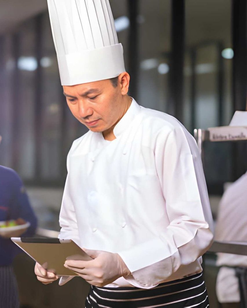 A head chef reviewing figures on a tablet during service